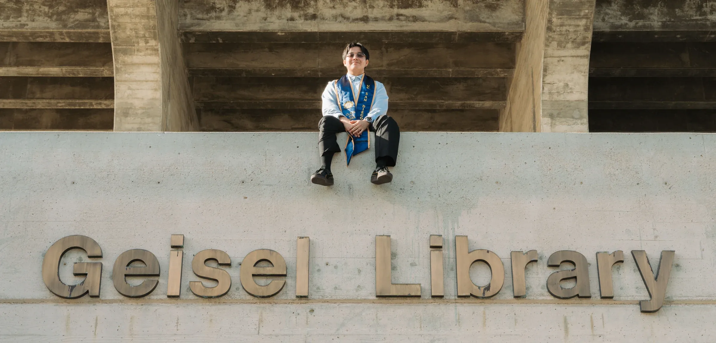 Collin Ong sitting above the Geisel Library sign at UC San Diego