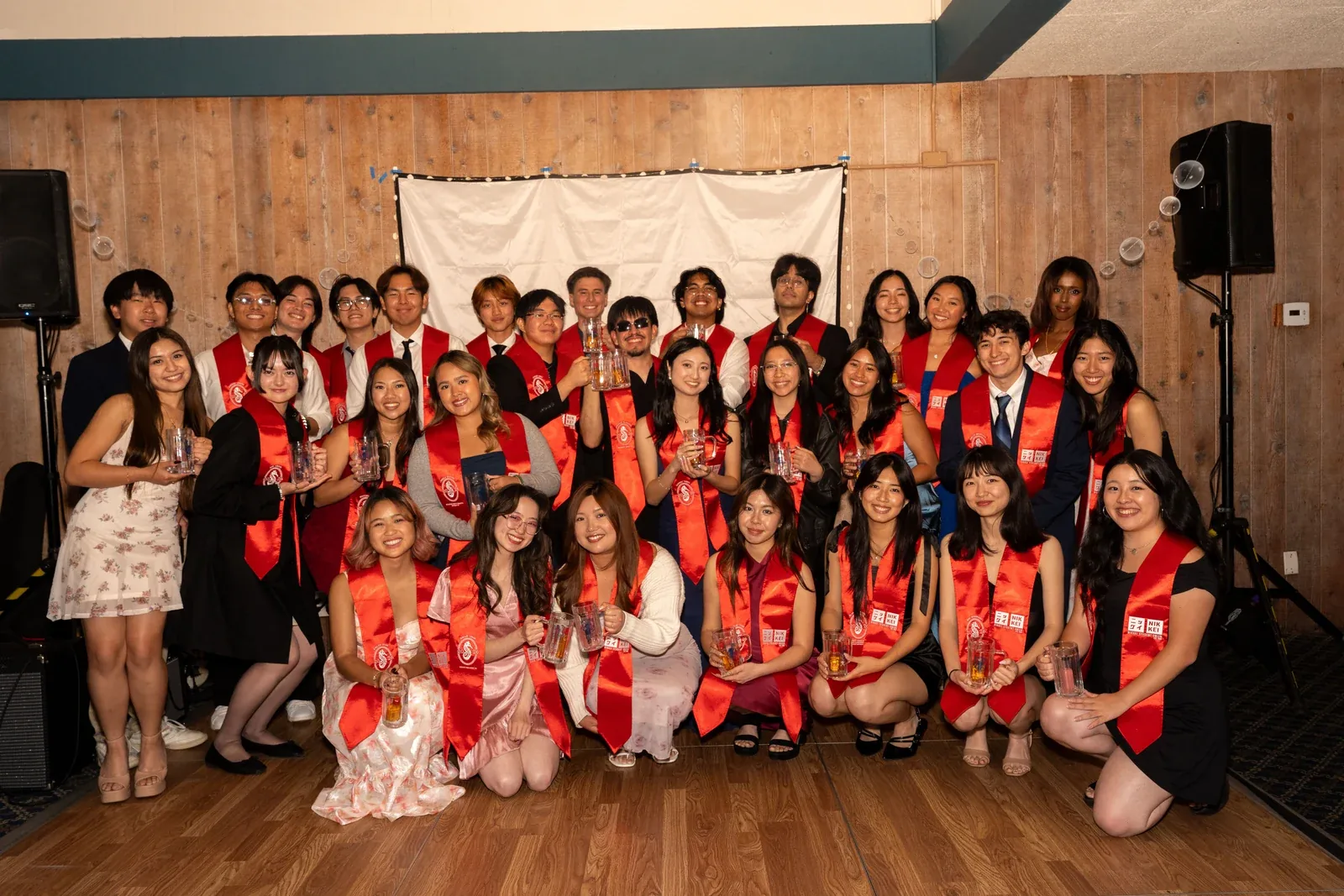 A large group in matching red and white, posed together in front of a backdrop indoors