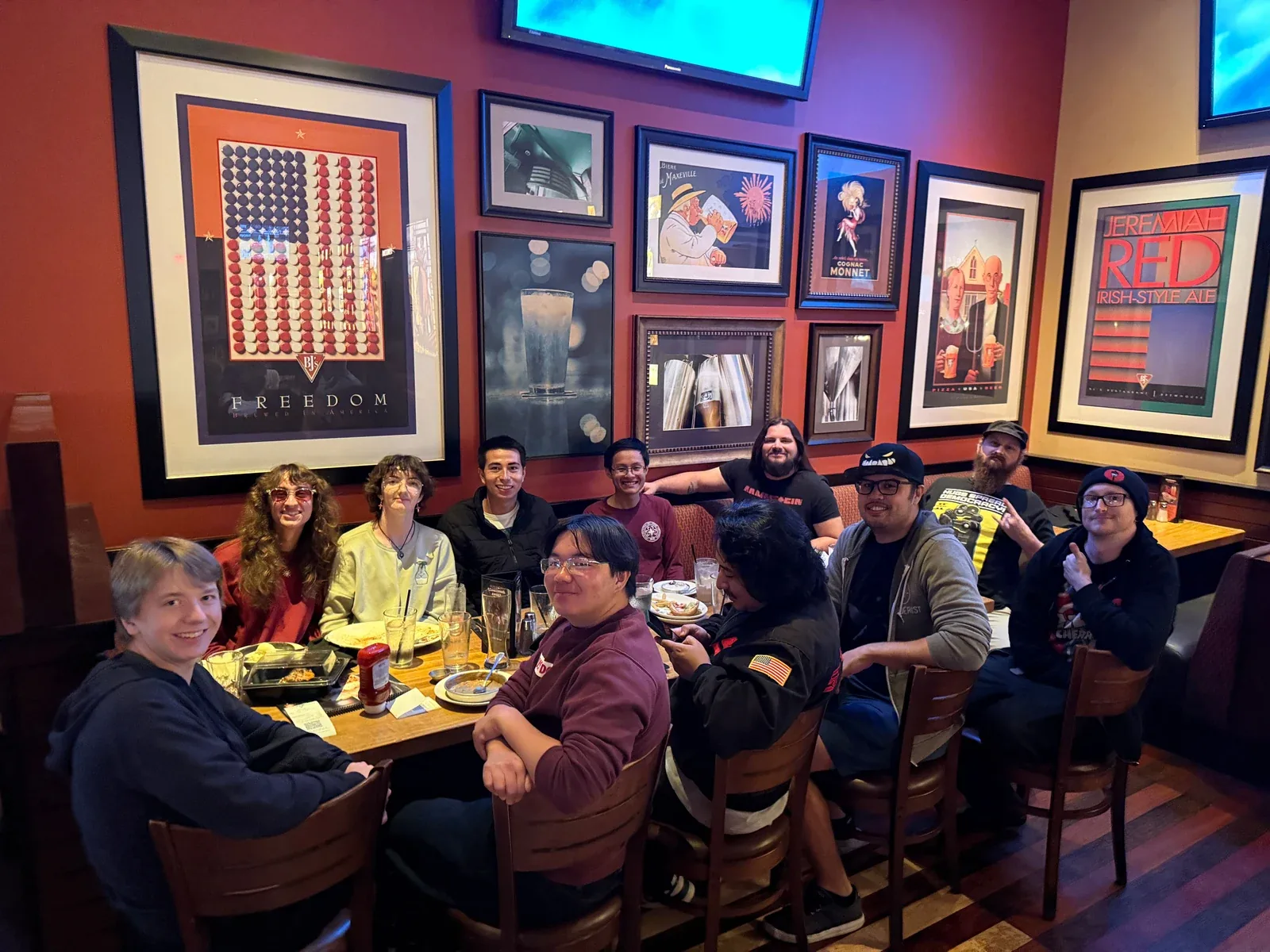 A group gathered around a table in a restaurant hung with framed artwork
