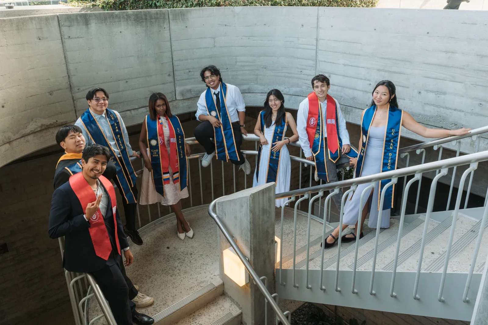 Graduates in stoles and cords on a concrete stairway on graduation day